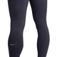 Nærbillede af en person, der bærer Nike Swift løbetights med høj talje, 7/8-længde og lommer, dame, i farven Gridiron/Reflective Silv. Disse løbetights med lommer har små, jævnt fordelt ventilationshuller på lårene og knæene for øget åndbarhed samt et diskret reflekterende Nike Swoosh-logo nederst på venstre ben. Refleksdetaljer sikrer øget synlighed under løbeture i svagt lys, mens de praktiske lommer giver ekstra funktionalitet på farten.