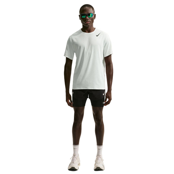En mand kigger fremad i en Nike Nk Dfadv Aroswft Ss Top, Herre, Summit White/Black med sorte Nike-shorts, hvide sokker og sneakers samt mørke solbriller. T-shirten er udstyret med Nikes avancerede Dri-FIT ADV-teknologi, der giver komfort.