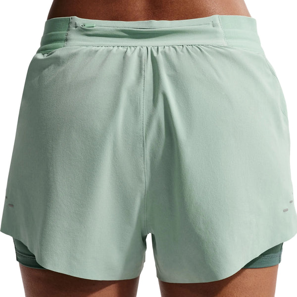 Nærbillede af ryggen på en person iført Nike Nk Swift Df Mr 2N1 shorts til kvinder i Steam/Mineral Slate/Reflective Silver med overlappende design, synlig linning og komfort fra Dri-FIT-teknologi.