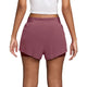 Der ses en person fra livet og ned, iført en hvid, kort top sammen med Nike Swift Mid-Rise 2-i-1-løbeshorts til kvinder i farvekombinationen Pink Smoke/Mystic Dates/Reflective Silver. Bagsiden fremhæver shortsenes elastiske linning og slidser i siderne samt et lagdelt design inspireret af Nike Swift-shortsene, der øger komforten og bevægelsesfriheden.