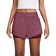 En person har en hvid crop top på samt Nike Swift Mid-Rise 2-i-1-løbeshorts til kvinder i farvekombinationen Pink Smoke/Mystic Dates/Reflective Silver, der har et dobbeltlagsdesign med Dri-FIT-teknologi – perfekt til træning. Billedet er beskåret fra skuldrene til midt på låret og viser det ikoniske Nike-logo nær den nederste højre kant af disse løbeshorts.