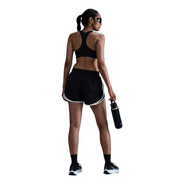 En kvinde iført Nike Tempo Mid-Rise løbeshorts med indvendig underbuks i farverne sort/sort/hvid/reflekterende sølv, en matchende sports-BH, strømper og løbesko står med ryggen til og holder en vandflaske i hånden, mens hendes hestehale og solbriller er klar til træningen.