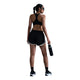 En kvinde iført Nike Tempo Mid-Rise løbeshorts med indvendig underbuks i farverne sort/sort/hvid/reflekterende sølv, en matchende sports-BH, strømper og løbesko står med ryggen til og holder en vandflaske i hånden, mens hendes hestehale og solbriller er klar til træningen.