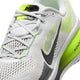 Nærbillede af Nike Vomero 18, Herre i farvekombinationen Photon Dust/Black-Volt – en hvid herreløbesko med neongule og grønne detaljer, et sort Nike Swoosh-logo og teksten »RUN« på tungen. Denne sportslige løbesko er fremstillet af mesh-materiale og har hvide snørebånd, der sikrer åndbarhed, støtte og maksimal komfort under hver eneste løbetur.