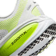 Nærbillede af Nike Vomero 18, herremodel i farven Photon Dust/Black-Volt, hvor ordet ZOOMX fremgår af den neongrønne støddæmpning. Mønsteret på ydersålen og en del af overdelen i mesh er synlige, hvilket viser den maksimale støddæmpning, som disse løbesko fra Nike tilbyder.