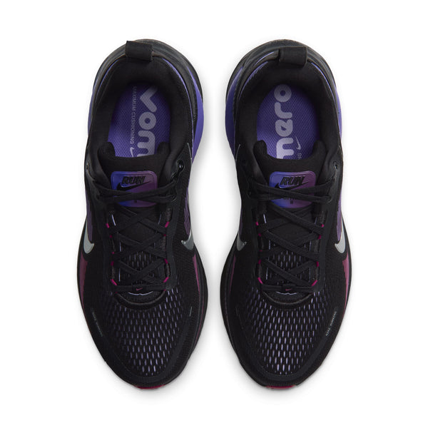 Et par Nike Vomero 18 Dame-løbesko i sort/metalsølv, set ovenfra. Indersålerne er forsynet med teksten »VOMERO« og »RUN« i hvid og lilla. Disse løbesko til kvinder er designet med maksimal dæmpning og har sorte snørebånd samt en overdel i mesh med en diskret farveovergang.