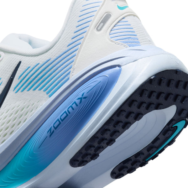 Nærbillede af Nike Vomero 18, Dame i White/Midnight Navy-Blue Fury. ZOOMX vises på mellemsålen, og ydersålen har sort og turkis slidbane med blå accenter for en behagelig løbesko.