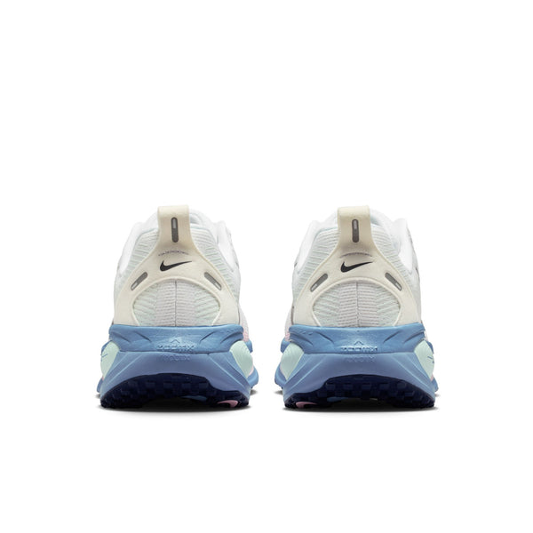 Et par Nike Vomero 18 løbesko til kvinder i farvekombinationen White/Midnight Navy-Work Blue set bagfra, hvor hælen, trækflapperne, Nike-logoerne og de blå, strukturerede ydersåler med maksimal støddæmpning for ekstra komfort fremhæves på en hvid baggrund.