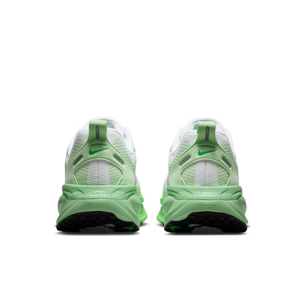 Et par Nike Vomero 18 Dame-løbesko i farvekombinationen hvid/metalsølv-illusiongrøn er afbilledet set bagfra på en hvid baggrund, hvor man kan se de synlige såler, de diskrete lysegrønne farveovergange og et lille Nike-logo øverst på hver hæl – hvilket gør dem til ideelle løbesko til kvinder med maksimal dæmpning for øget komfort.