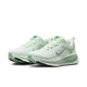 Et par Nike Vomero 18 Dame løbesko i Barely Green/Metallic Silver-Steam med grønne detaljer og ZoomX-mellemsål for maksimal dæmpning, vises på en hvid baggrund.