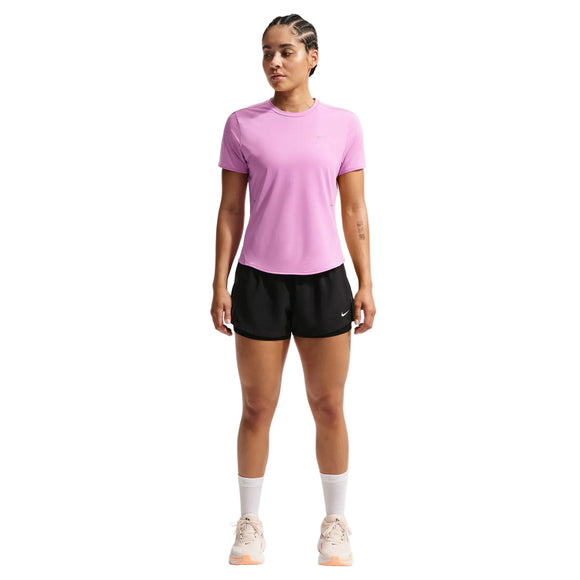 En person står med ansigtet fremad i en Nike Swift SS Løbetop til kvinder (Lt Magenta/Reflective Silver), sorte shorts, hvide strømper midt på læggen og lyse sneakers - en ideel tilføjelse til enhver løbegarderobe - på en hvid baggrund.