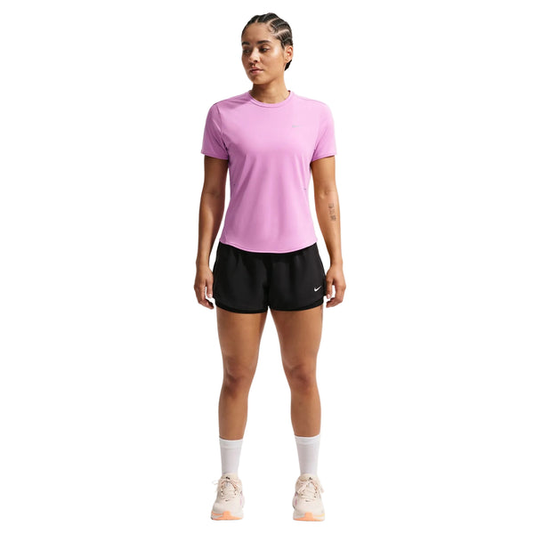 En person står med ansigtet fremad i en Nike Swift SS Løbetop til kvinder (Lt Magenta/Reflective Silver), sorte shorts, hvide strømper midt på læggen og lyse sneakers - en ideel tilføjelse til enhver løbegarderobe - på en hvid baggrund.