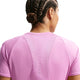 Person med fletninger set bagfra iført Nike Swift SS Running Top til damer i Lt Magenta/Reflective Silv - en svedtransporterende løbe-T-shirt med meshdetaljer og små vertikale reflekser. Perfekt til din løbegarderobe.