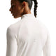 En person med en flettet hestehale ses set bagfra iført Nike Swift UV Half Zip-løbetrøje til kvinder i farven Sail/Reflective Silver. Den hvide, langærmede trøje har en høj krave og diskrete reflekterende detaljer. Billedet fremhæver pasformen og teksturen i det svedtransporterende stof, der er udviklet til at give fremragende komfort og UV-beskyttelse under udendørsaktiviteter.