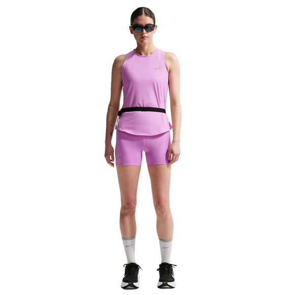 En kvinde er iført en Nike Nk Swift Df Tank Top, Dame, i Lt Magenta/Reflective Silv med matchende pink shorts, sort taljebælte, hvide knæstrømper, sorte sneakers og solbriller, mens hun står på en hvid baggrund.