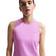 En person med kort brunt hår er iført en ærmeløs, lys magenta Nike Nk Swift Df Tank Top (Dame) med reflekterende sølvdetaljer. Svage tatoveringer på armen er synlige, og baggrunden er helt hvid.