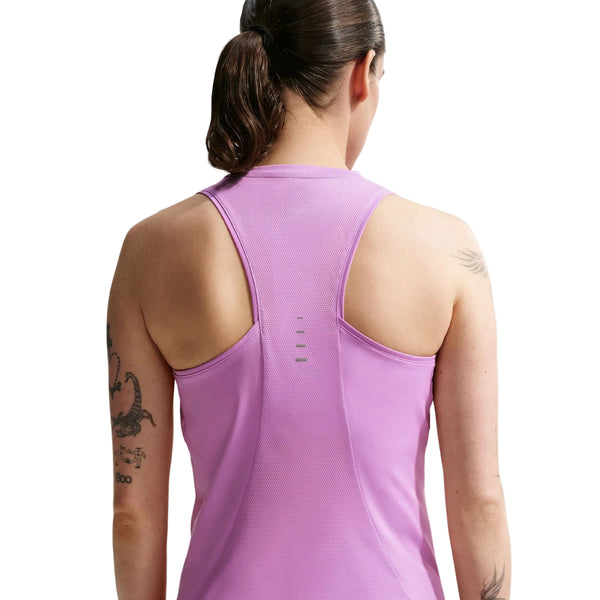 En kvinde med mørkt hår i hestehale ses bagfra iført en ærmeløs Nike Nk Swift Df Tank Top til kvinder i Lt Magenta/Reflective Silv. Tatoveringer er synlige på hendes venstre arm mod en hvid baggrund.