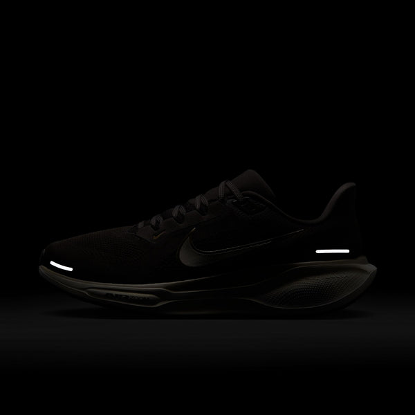 A Nike Pegasus 41 Ji løbesko herre i farven Medium Ash/Mtlc Gold Grain-Summit White vises på mørk baggrund. Skoen har lav profil, reflekterende detaljer på hæl og tå samt en tekstureret sål med ReactX-skum og snørebånd.