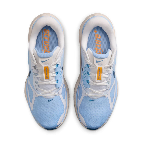 Et par Nike Structure Plus Dame-løbesko i farvekombinationen White/Mystic Navy-Aluminum-Sundial, set ovenfra med »stuck« i orange på venstre tunge, »ambush« på højre og gule mærker på snørebåndene – for stil og stabilitet.