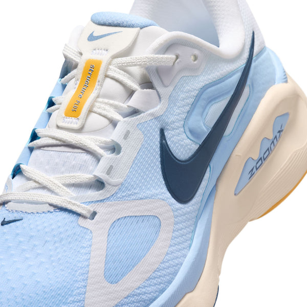 Nærbillede af Nike Structure Plus-løbesko til kvinder i farvekombinationen White/Mystic Navy-Aluminum-Sundial, med en mørkeblå Swoosh og hvide snørebånd. Skoen er designet med henblik på stabilitet og støtte og har en stødabsorberende mellemsål.