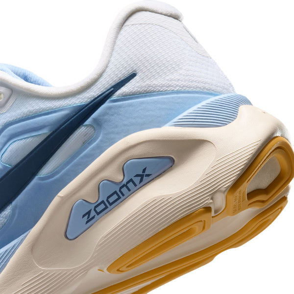 Nærbillede af hælen på Nike Structure Plus, Dame i farvekombinationen White/Mystic Navy-Aluminum-Sundial, med et mørkeblåt Swoosh-logo, »ZOOMX«-mærkning på mellemsålen og en cremefarvet/gul ydersål, der er udviklet med henblik på stabilitet og støtte mod overpronation.