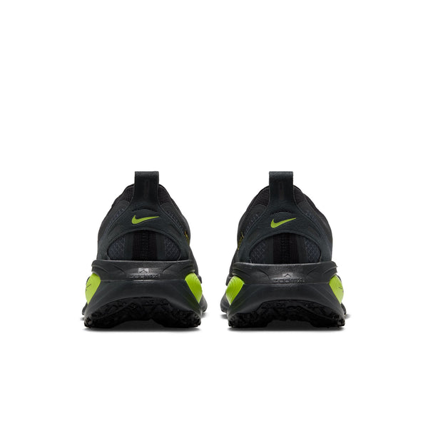 Et par Nike Vomero 18 GORE-TEX-løbesko til mænd i farvekombinationen Anthracite/Black-Lemon Venom ses set bagfra på en hvid baggrund. Det ikoniske Nike-logo pryder hver hæl, og det lave design med strukturerede såler gør disse sko til et ideelt par vandtætte løbesko.