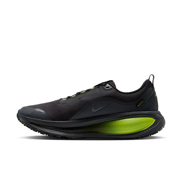 En sort Nike Vomero 18 GORE-TEX herreløbesko i farvekombinationen Anthracite/Black-Lemon Venom har et lavt design med et diskret logo og en iøjnefaldende, oval mellemsål i farven Lemon Venom. Denne vandtætte løbesko kombinerer sorte snørebånd, en struktureret sål og et elegant design, der sikrer både høj ydeevne og et moderne udseende.