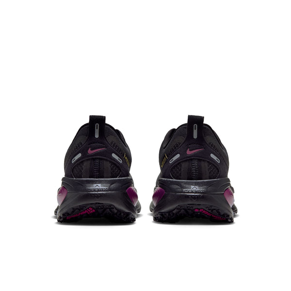Bagfra-billede af to sorte Nike Vomero 18 Gore-Tex-løbesko til kvinder i farvekombinationen sort/metallisisk sølv-True Berry med magenta-detaljer og strukturerede såler.