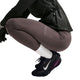 En person iført mørke sportsleggings og Nike Vomero 18 Gore-Tex, Dame, sort/metalsølv-True Berry løbesko sidder på hug foran en ensfarvet baggrund.