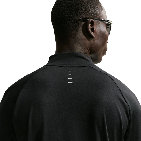 Der ses en person set bagfra, der bærer Nike Stride Half Zip Midlayer-løbetrøje til mænd i farven sort/reflekterende sølv. Den sorte trøje har fire små hvide vandrette streger, der er trykt lodret på den øverste del af ryggen, på en hvid baggrund. Personen bærer desuden sorte solbriller.