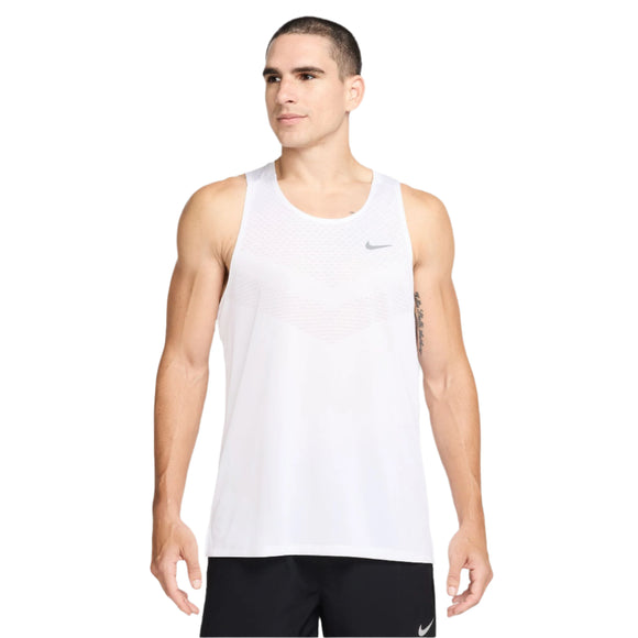 En mand står med ansigtet fremad og afslappede arme iført Nike Dri-Fit Adv Running Tank Top, Herre, White/Reflective Silver og sorte Nike-shorts. Den svedtransporterende tank top holder ham kølig mod en almindelig hvid baggrund.
