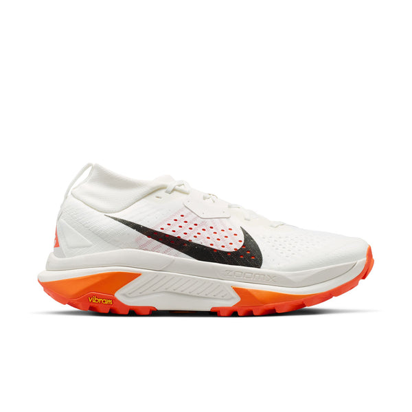En Nike ACG Zegama herre trail løbesko i Summit White/Black-Phantom-Safety Orange med mesh-overdel, sort swoosh og Vibram Megagrip-sål, vist fra siden på hvid baggrund.