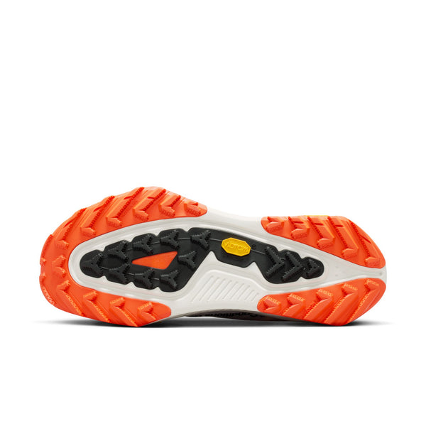 Billedet viser sålen på Nike ACG Zegama trail løbesko til mænd i Summit White/Black-Phantom-Safety Orange med orange og sort gummimønster, en hvid midterdel og et gult Vibram Megagrip-logo for greb og holdbarhed.