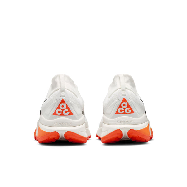 Et par Nike ACG Zegama trailsko til mænd i Summit White/Black-Phantom-Safety Orange, set bagfra, med orange Vibram Megagrip-såler og fede orange ACG-trekantlogoer på hælene.