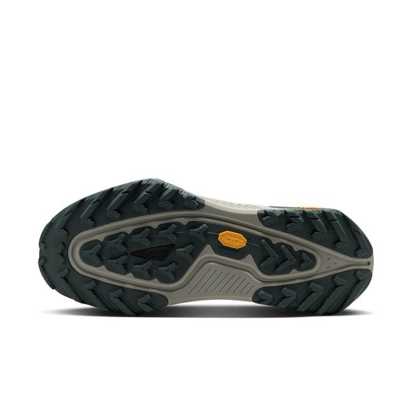 Billedet viser en underside af trailskoen Nike ACG Zegama (Herre, Spruce Fog/Black Spruce-Sea Glass-Black), som har en grå og sort Vibram-sål med et karakteristisk mønster og et gult Vibram-logo i midten. Sålen er udstyret med Vibram Megagrip-teknologi, der sikrer fremragende greb på ujævnt terræn.