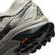 Nærbillede af hælen og ydersålen på Nike ACG Zegama til mænd i farvekombinationen Spruce Fog/Black Spruce-Sea Glass-Black, med et struktureret mønster, der giver godt greb, samt det sorte Vibram Megagrip-logo, stof med camouflagemønster og delvist Nike-logo i beige. Skoen fremstår slidstærk og designet til udendørs brug med et robust design.