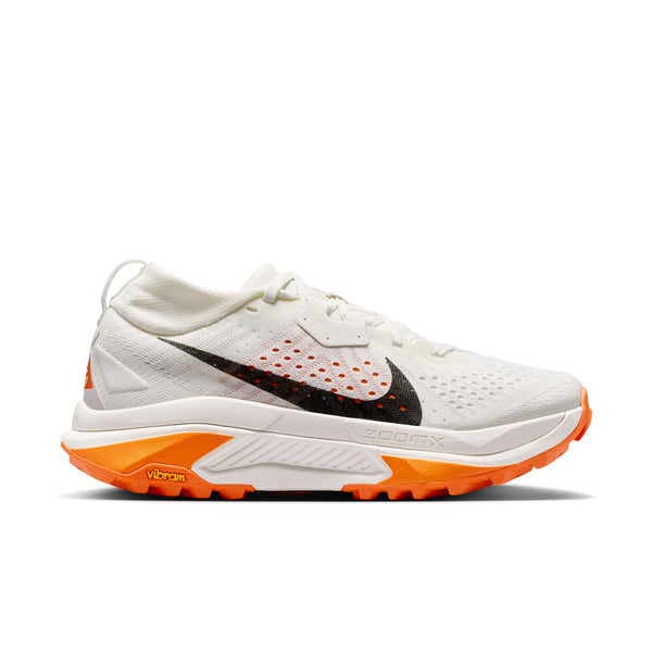 Nike ACG Zegama Dame i Summit White/Black-Phantom-Safety Orange har en sort swoosh, orange detaljer og ZOOMX plus Vibram Megagrip for sikkert greb - perfekt til eventyrlige trailløb.