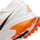 Nærbillede af hælen og sålen på en Nike ACG Zegama Dame trailsko i Summit White/Black-Phantom-Safety Orange, der viser orange og sort Vibram Megagrip-mønster, Vibram-logoet og et delvist Nike-logo på siden.