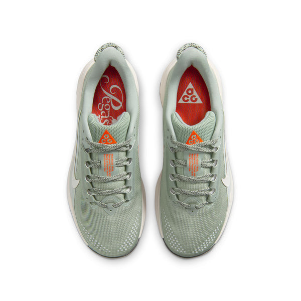 Et par Nike ACG Pegasus Trail Dame i Jade Horizon/Phantom-Light Silver set ovenfra, med hvide såler, orange detaljer på tungen, en hvid Swoosh og orange indersåler med hvid branding, forstærket af behagelig ReactX-skum.