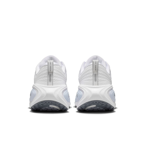 Et par Nike Vomero Plus Herre i White/Grey Fog-Hydrogen Blue-Cool Grey set bagfra, med strukturerede såler, grå gummiydersåler, trækflige i hælen og lyseblå detaljer på mellemsålen.