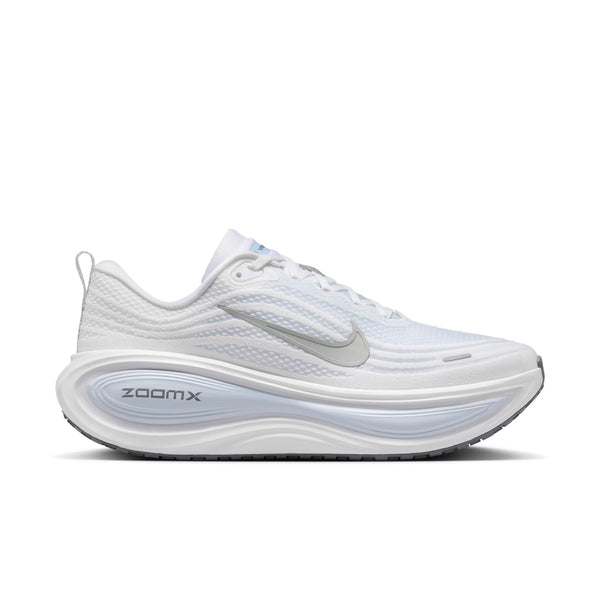 Nike Vomero Plus, Herre, i White/Grey Fog-Hydrogen Blue-Cool Grey har en sølvfarvet swoosh, overdel i mesh, støddæmpet sål med ZOOMX-mellemsål. Denne mængdetræningssko er vist fra venstre side på en almindelig hvid baggrund.