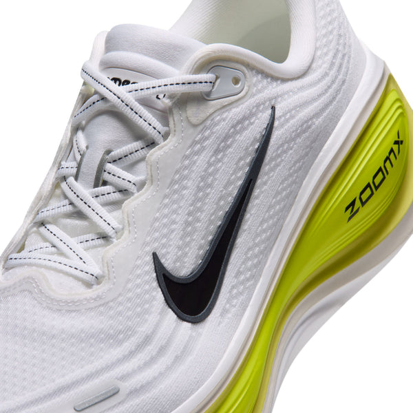 Nærbillede af en Nike Vomero Plus-løbesko i farvekombinationen HVID/SORT-LEMON VENOM-ELECTRIC YELLOW med hvid overdel, sort Swoosh og gul hælstabilisator.