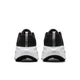 Et par Nike Vomero Plus-løbesko til kvinder i farvekombinationen Black/White-Cool Grey-Mtlc Dark Grey set bagfra, med struktureret overdel, tykke hvide såler, der sikrer maksimal komfort, og en reflekterende stribe på hver hæl. Baggrunden er ensfarvet hvid.