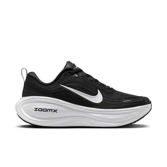 En Nike Vomero Plus-løbesko til kvinder i farvekombinationen Black/White-Cool Grey-Mtlc Dark Grey, med en sort mesh-overdel, hvide detaljer, sorte snørebånd, et markant hvidt Nike Swoosh-logo og teksten »ZOOMX« på den hvide skumsål. Skoen, der her vises i profil mod en hvid baggrund, er designet til at give maksimal komfort.