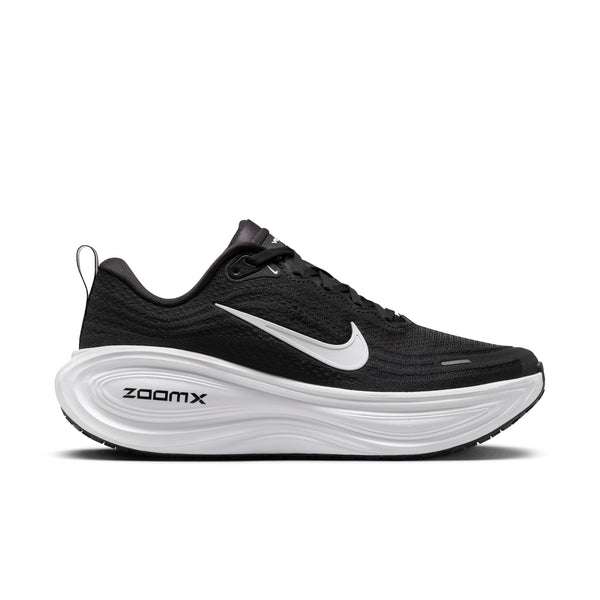 En Nike Vomero Plus-løbesko til kvinder i farvekombinationen Black/White-Cool Grey-Mtlc Dark Grey, med en sort mesh-overdel, hvide detaljer, sorte snørebånd, et markant hvidt Nike Swoosh-logo og teksten »ZOOMX« på den hvide skumsål. Skoen, der her vises i profil mod en hvid baggrund, er designet til at give maksimal komfort.