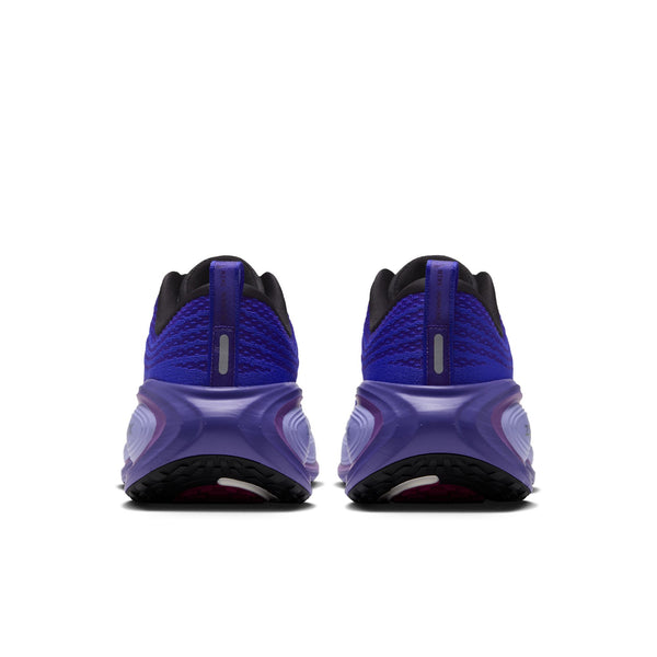 Bagfra-billede af Nike Vomero Plus til kvinder i farvekombinationen SORT/METALLISK SØLV-PERSISK VIOLET, der viser en struktureret hæl, en reflekterende stribe og en tyk, buet sål med synlige mønstre. Disse løbesko fra Nike er designet til maksimal komfort og er placeret side om side på en hvid baggrund.