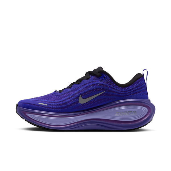 Et sidebillede af Nike Vomero Plus Dame-løbeskoen i farvekombinationen SORT/METALLISK SØLV-PERSISK VIOLET, der viser en overdel i mesh med sorte snørebånd, et metallisk sølvfarvet Swoosh-logo og en tyk, buet lilla ZoomX-mellemsål. Denne model er designet som en løbesko, der sikrer maksimal komfort, og har desuden en praktisk hælstropp samt en slidstærk sort ydersål.