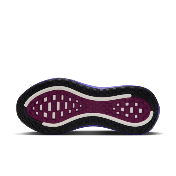 Billedet viser undersiden af Nike Vomero Plus Dame-løbeskoen i farvekombinationen BLACK/METALLIC SILVER-PERSIAN VIOLET, hvor mønsteret på sålen fremstår i farverne sort, hvid og persisk violet. Sålen er udstyret med forskellige riller og rektangulære segmenter, der forbedrer grebet og fleksibiliteten for at sikre maksimal komfort. Skoen er fotograferet på en hvid baggrund.