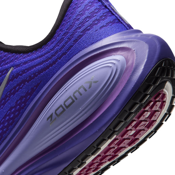 Nærbillede af en lilla Nike Vomero Plus Dame-løbesko i farvekombinationen BLACK/METALLIC SILVER-PERSIAN VIOLET, der fremhæver hælområdet, overdelen i struktureret mesh og ZOOMX-logoet på den stødabsorberende mellemsål, der sikrer maksimal komfort. Ydersålen har et synligt mønster med sektioner af sort og lilla gummi.