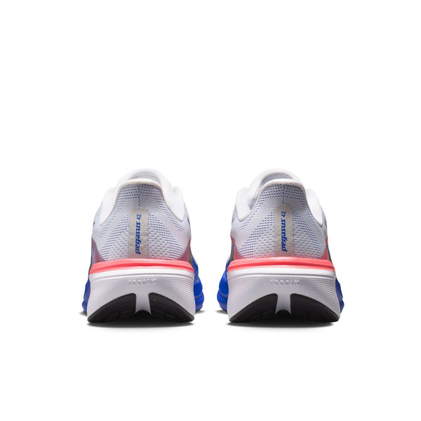 Et par Nike Pegasus 42 løbesko til mænd i farvekombinationen Hvid/Sort-Racerblå-Atomic Pink, set bagfra, viser mærkenavnet NIKE på hælen og fremhæver ydersålens design. Disse sko, der er inspireret af klassiske Pegasus-modeller og udstyret med avanceret ReactX-skumstøddæmpning, er placeret side om side på en hvid baggrund.